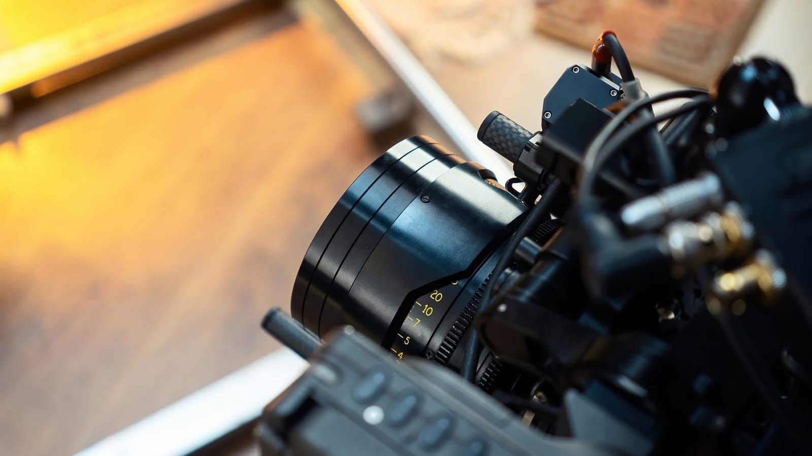 Close de uma lente cinematográfica com marcações de foco acoplada a uma câmera sobre trilho de travelling.
